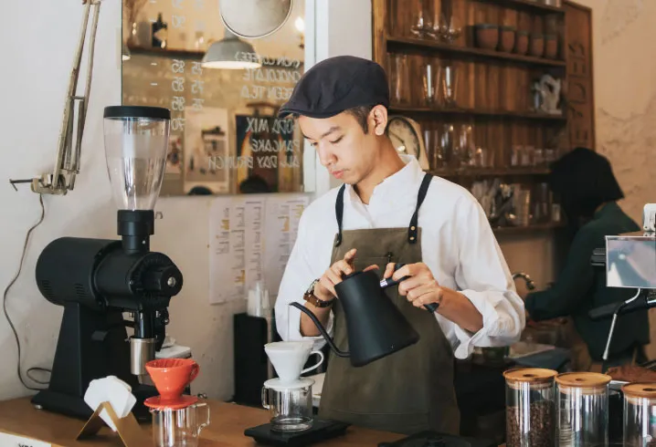 Um barista servindo café em uma cafeteria.