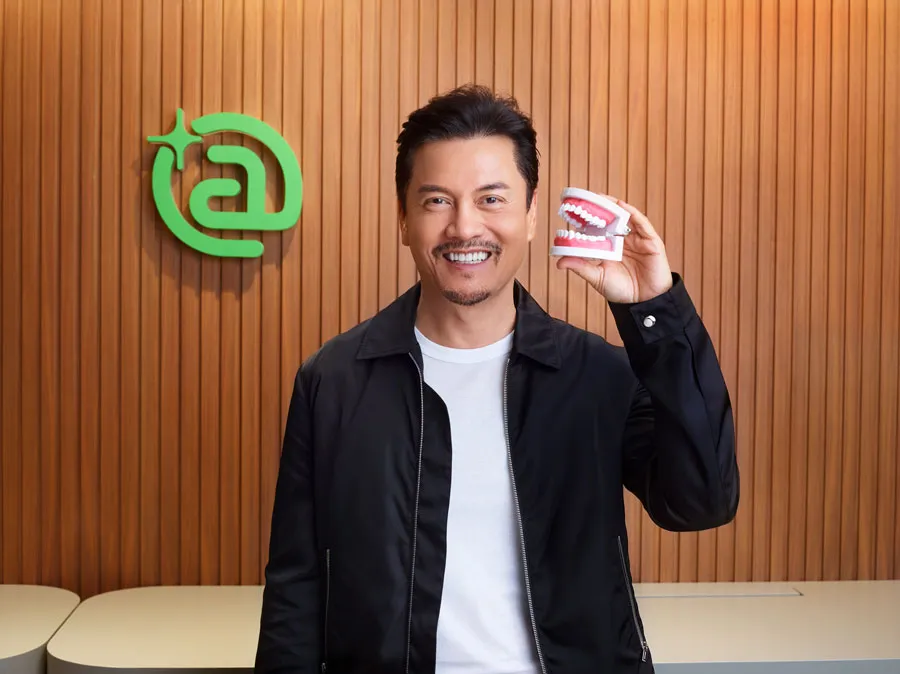 Um homem está segurando uma prótese dentária na mão.