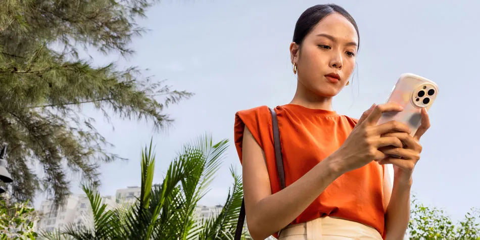 Uma mulher ao ar livre olhando para o celular com atenção