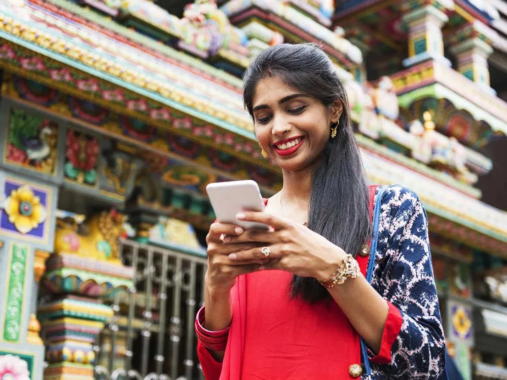 Wanita tersenyum sambil melihat teleponnya di luar ruangan