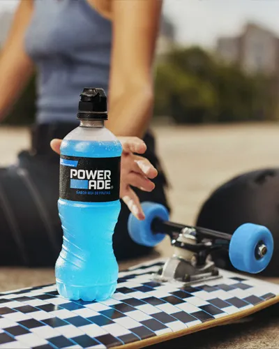 स्केटबोर्ड पर रखी Powerade ड्रिंक को थामने के लिए, हाथ बढ़ाती हुई एक महिला