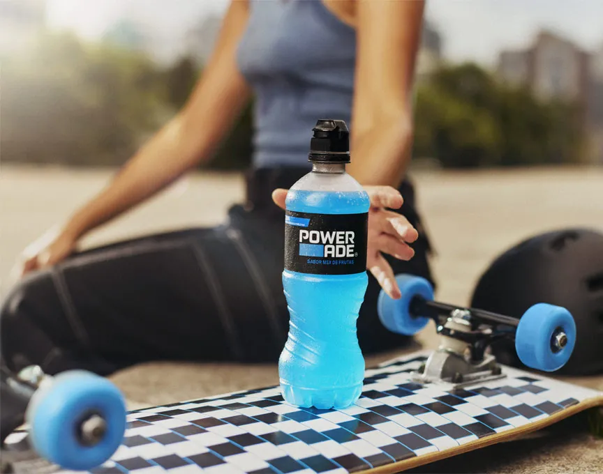 Una mujer toma su bebida Powerade que está encima de una tabla de skate.