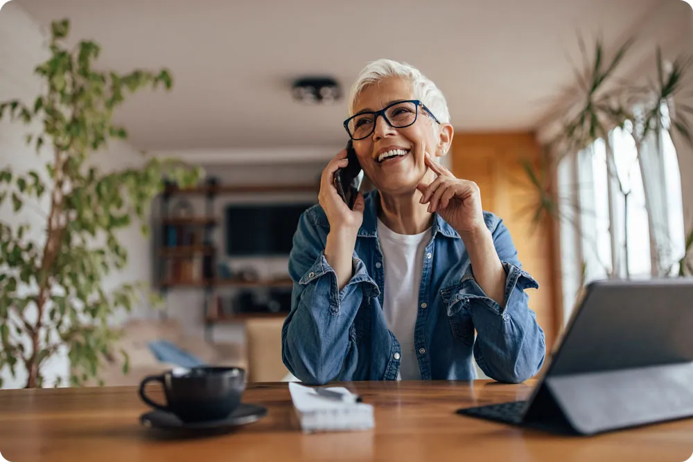 Une femme, assise à une table, est au téléphone.
